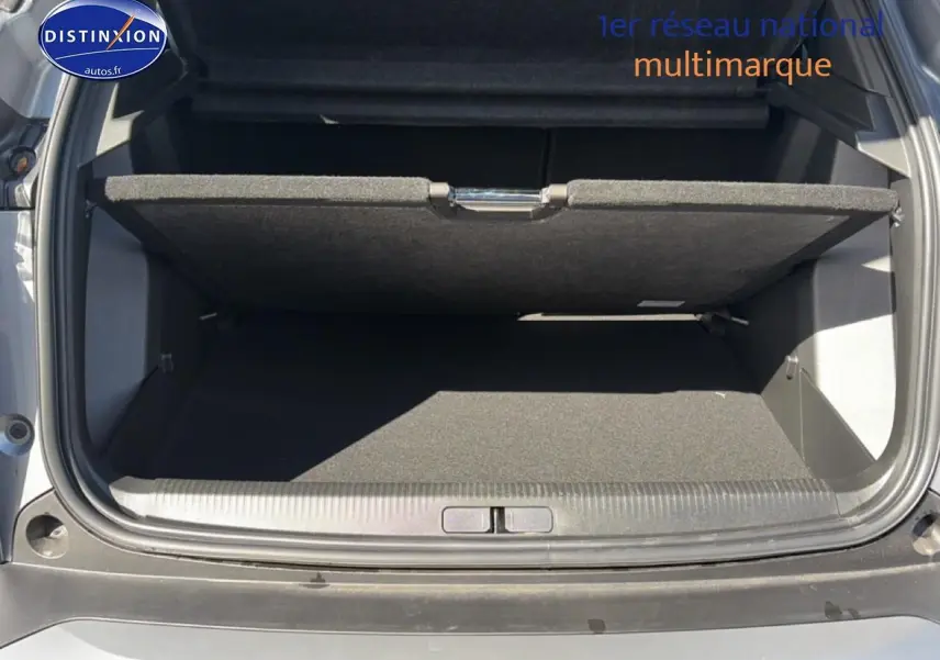 Coffre ouvert vu de l'arrière d'un Peugeot 2008 gris artense avec cache-bagages partiellement relevé.