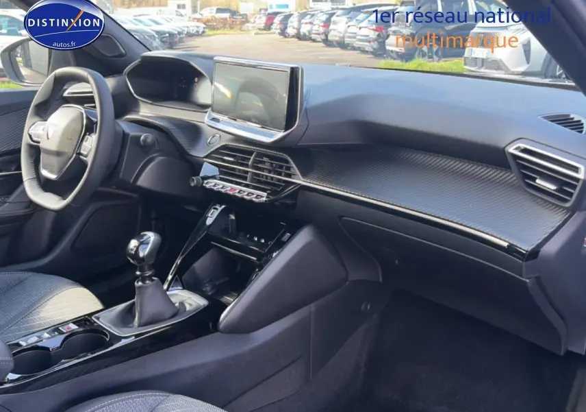 Intérieur avant droit du Peugeot 2008 1.2 100 Allure 2025 avec tableau de bord noir et écran tactile central.