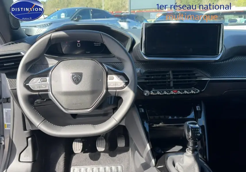 Vue intérieure frontale du tableau de bord et volant noir de la Peugeot 2008 gris Artense avec boîte manuelle.