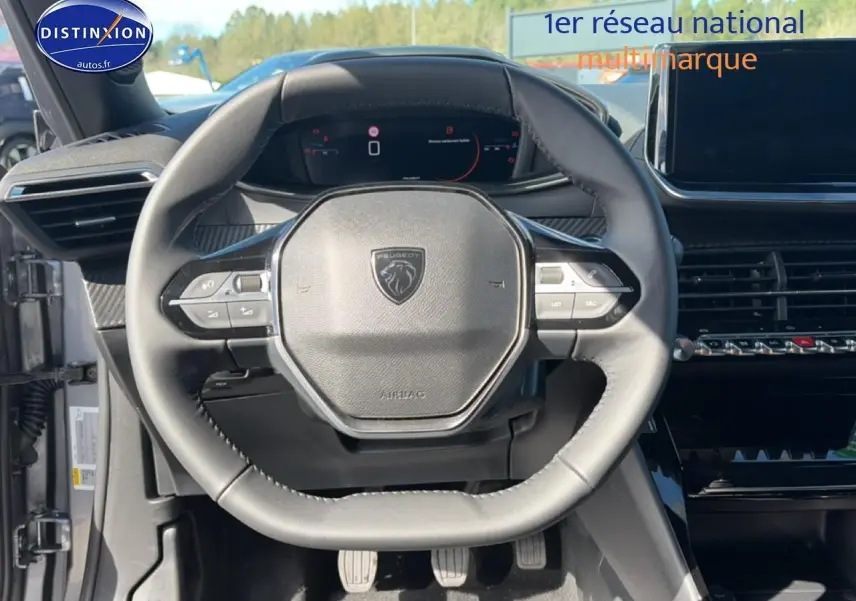 Vue rapprochée du volant multifonction noir de la Peugeot 2008 2025 avec tableau de bord numérique en arrière-plan.