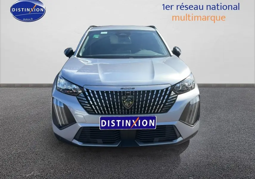 Vue frontale d'un Peugeot 2008 gris artense avec calandre verticale distinctive et phares LED allumés.