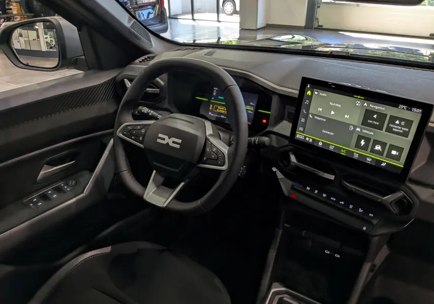 Vue intérieure côté conducteur du Dacia Duster Hybrid-G 150 CH 4x4 Journey avec tableau de bord numérique et écran tactile central.
