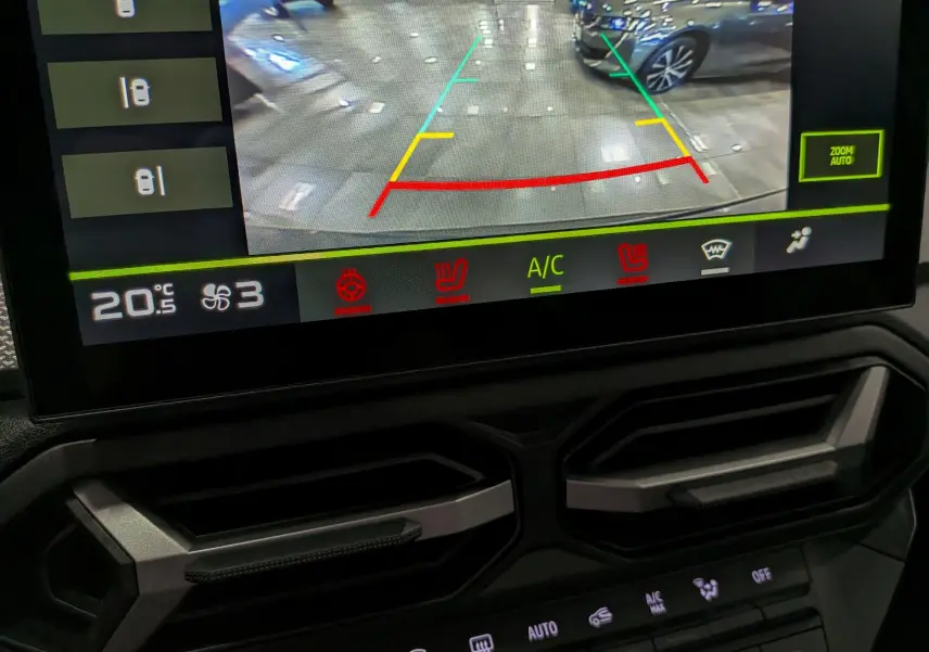 Vue intérieure sur l'écran de caméra de recul du Dacia Duster Vert Cèdre, avec commandes climatisation visibles en dessous.