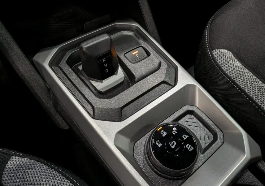 Gros plan sur la console centrale du Dacia Duster Hybrid-G 150 CH 4x4, montrant le levier de vitesse automatique et la molette de modes de conduite.