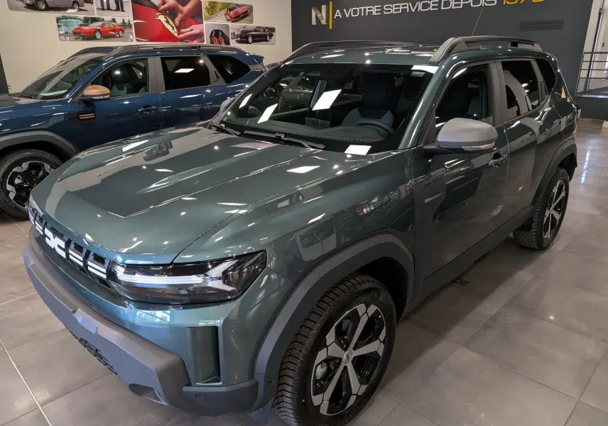 Vue 3/4 avant droit du Dacia Duster Hybrid-G 150 CH 4x4 en Vert Cèdre, avec jantes biton et détails noirs contrastants.
