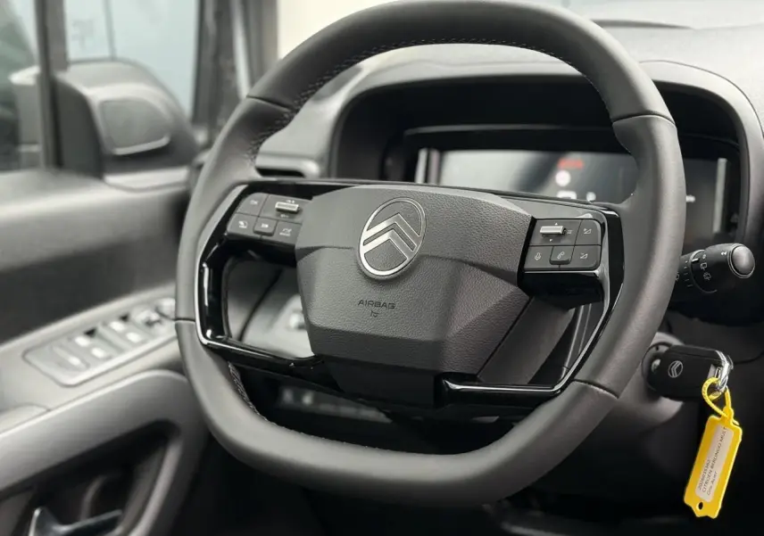 Vue rapprochée du volant multifonctions cuir noir de Citroën Berlingo Multispace 2026 avec logo chromé central.