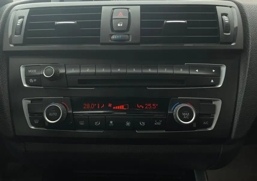 Vue rapprochée du tableau de bord noir de la BMW Série 2 Coupé F22 blanc, avec commandes climatisation et radio visibles.