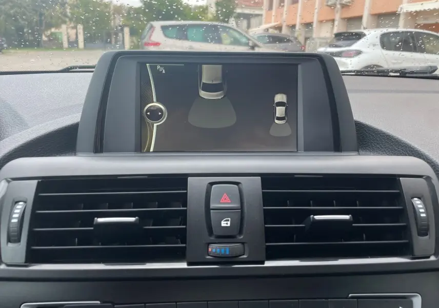 Vue rapprochée de l'écran central et des commandes de ventilation d'une BMW Série 2 Coupé F22 blanche de 2014.