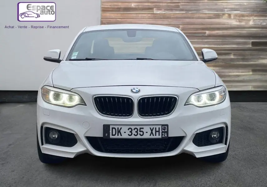 Vue frontale d'une BMW Série 2 Coupé F22 blanche avec phares allumés et calandre M Sport distinctive.