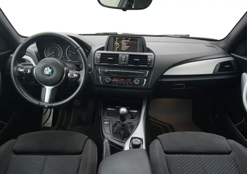 Vue intérieure avant du tableau de bord et volant M Sport d'une BMW Série 2 Coupé F22 blanche de 2014 avec boîte manuelle.