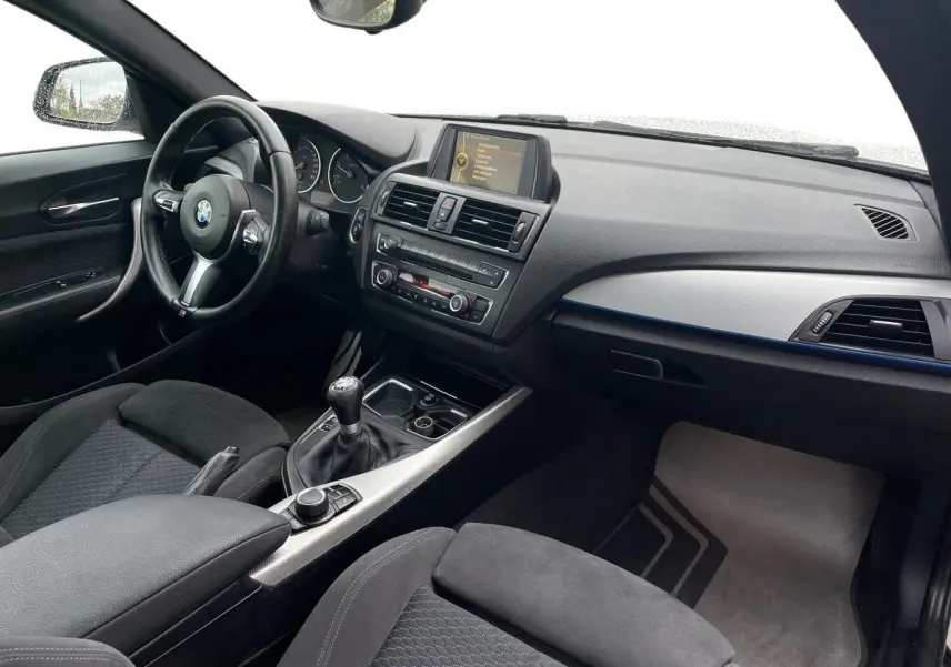 Intérieur noir de BMW Série 2 Coupé F22 220d M Sport 2014, vue côté conducteur avec boîte manuelle et tableau de bord moderne.