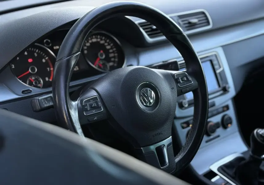 Vue rapprochée du volant en cuir noir multifonction de la Volkswagen Passat CC 2015 avec tableau de bord et console centrale visibles.
