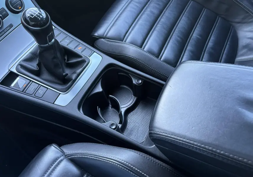 Gros plan intérieur sur la console centrale et la sellerie cuir noire de la Volkswagen Passat CC 1.4 TSI 2015 avec levier de vitesses manuel.