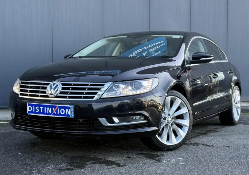 Volkswagen Passat CC 1.4 TSI 2015 en Deep Black, vue 3/4 avant avec jantes alliage 18 pouces et phares allumés.