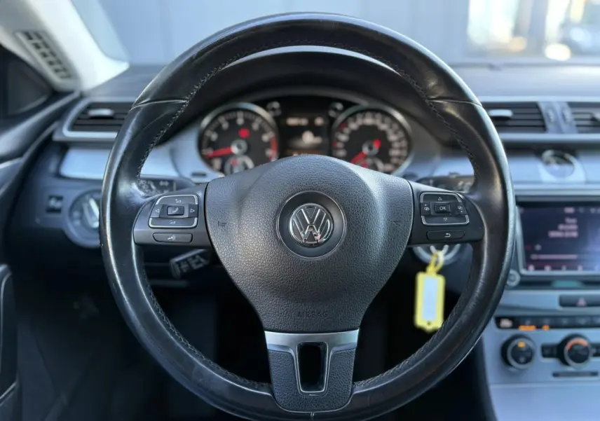 Vue centrée sur le volant cuir multifonction noir du Volkswagen Passat CC 2015, avec tableau de bord et console en arrière-plan.