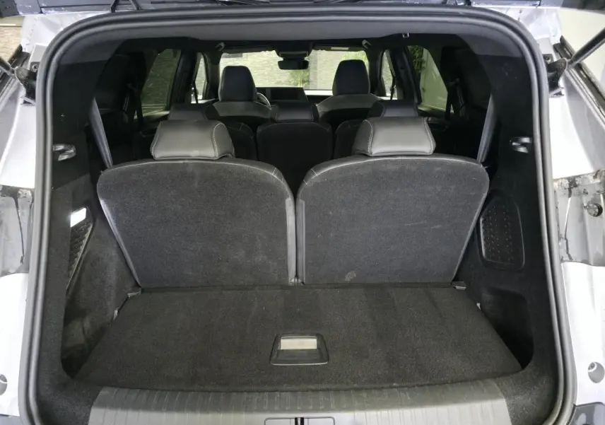 Coffre ouvert vu de l'arrière d'un Peugeot 5008 gris 2025, banquette 3e rangée relevée et intérieur noir.