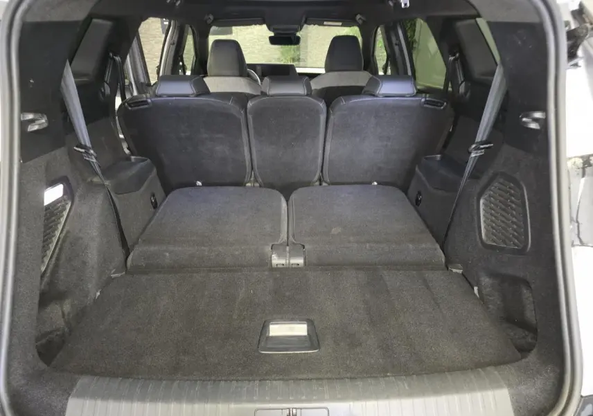 Vue du coffre arrière ouvert d’un Peugeot 5008 gris 2025 avec banquette rabattue et intérieur noir.