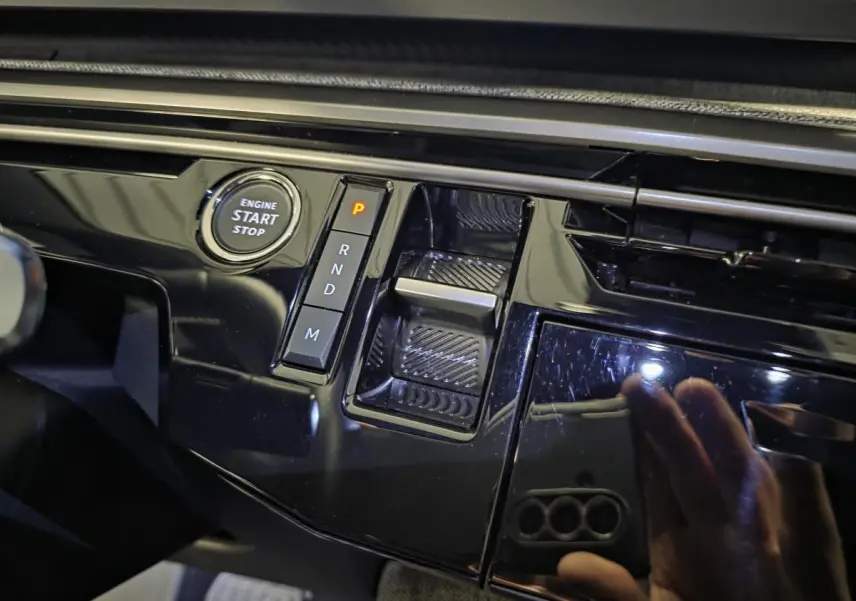 Gros plan sur la console centrale noire laquée du Peugeot 5008 hybride 2025 avec bouton start/stop et sélecteur de boîte automatique.