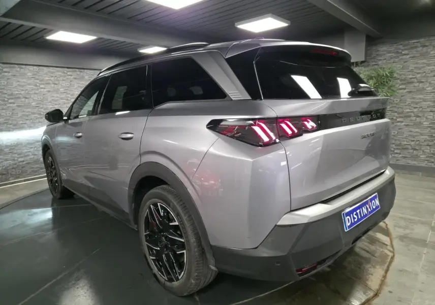 Vue 3/4 arrière droite du Peugeot 5008 gris métallisé avec feux arrière LED à 3 griffes et jantes alliage noires.