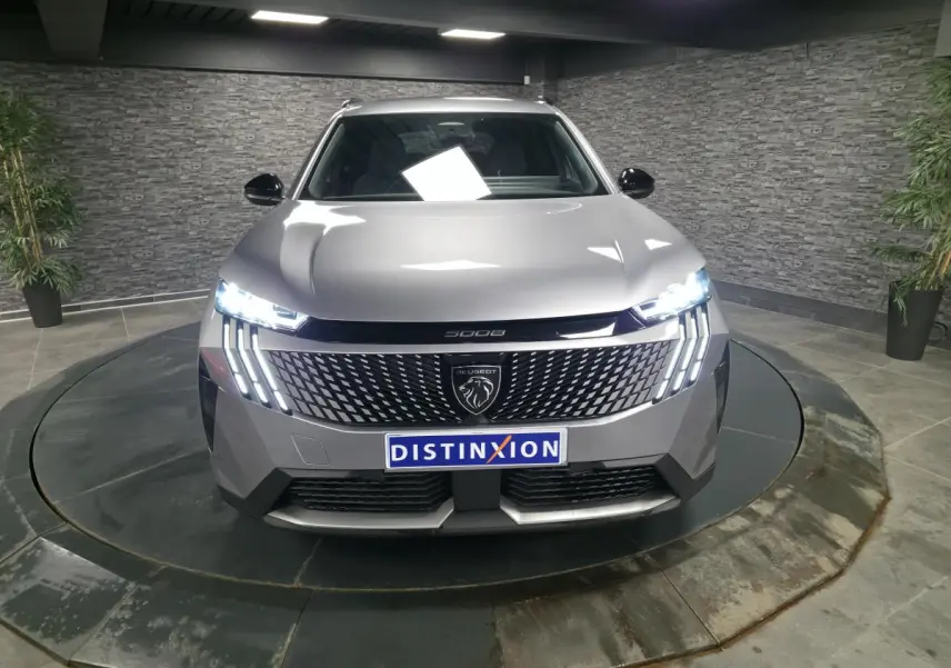 Vue frontale d'un Peugeot 5008 gris métallisé 2025 avec feux LED allumés et calandre au lion distinctif.