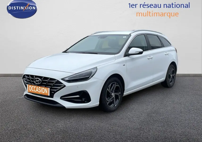 Hyundai i30 SW blanc polaire vue 3/4 avant droit, avec calandre noire et jantes alliage sombres.