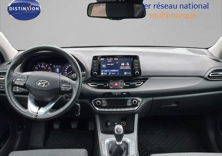 Vue intérieure avant de la Hyundai i30 SW 2021, tableau de bord gris noir avec écran tactile et boîte manuelle.
