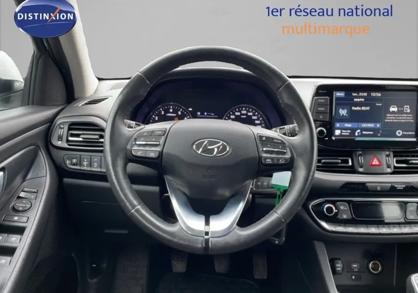 Vue intérieure centrée sur le volant noir de la Hyundai i30 SW 2021 avec tableau de bord et écran tactile visibles.
