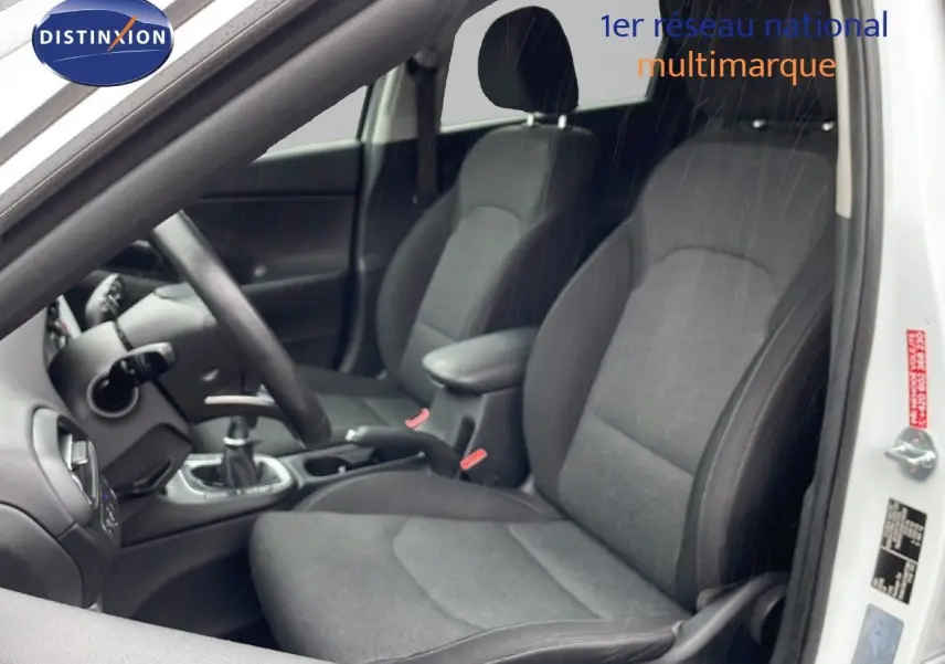 Vue intérieure côté conducteur de la Hyundai i30 SW blanche, sièges tissu gris foncé et volant multifonction.