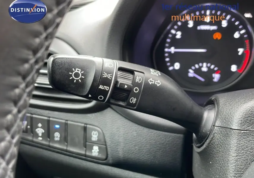 Gros plan sur la commande des feux et clignotants à gauche du volant dans l’habitacle noir d’une Hyundai i30 SW 2021.
