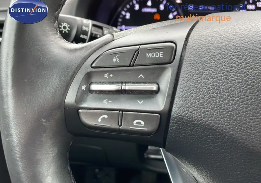 Gros plan sur les commandes au volant côté gauche de la Hyundai i30 SW blanc polaire, avec tableau de bord en arrière-plan flou.