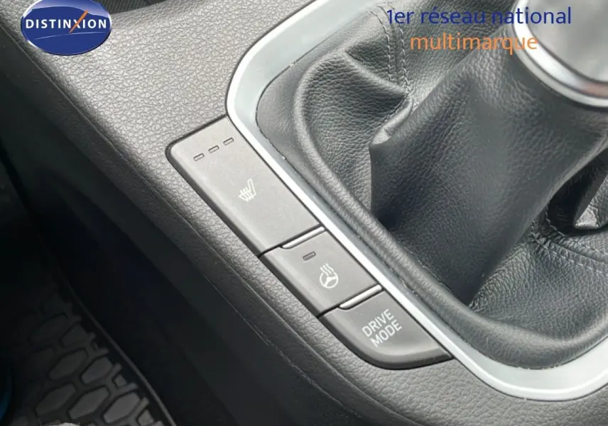 Gros plan sur la console centrale noire de la Hyundai i30 SW blanche, montrant le levier de vitesses manuel et les boutons de chauffage et mode de conduite.