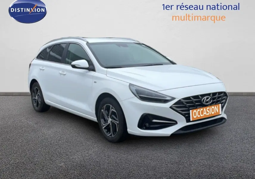 Vue 3/4 avant d'une Hyundai i30 SW blanche polaire avec calandre noire et jantes alliage bicolores.