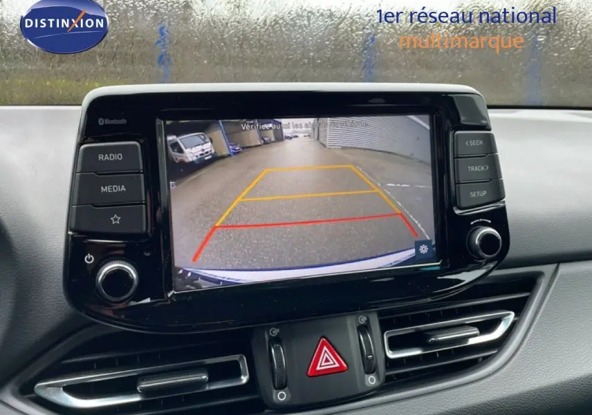 Vue rapprochée de l'écran central affichant la caméra de recul d'une Hyundai i30 SW blanche polaire.
