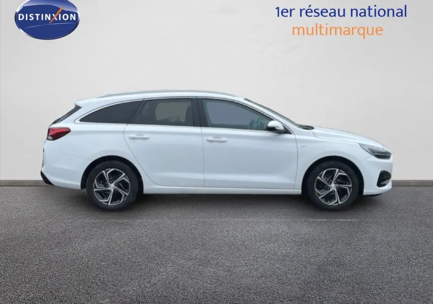 Vue de profil côté gauche d'une Hyundai i30 SW blanc polaire avec jantes alliage et vitres teintées.