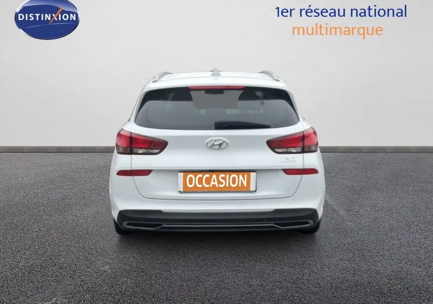 Vue arrière d'une Hyundai i30 SW blanche polaire, avec feux arrière rouges et plaque "OCCASION" visible.