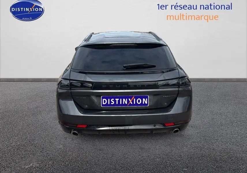 Vue arrière d'un Peugeot 508 SW Hybrid gris titane avec vitres arrière surteintées et double sortie d'échappement.