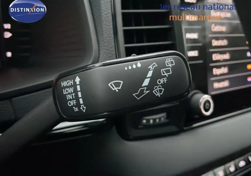 Gros plan sur la commande des essuie-glaces dans l’habitacle d’une Skoda Karoq argent 2025, avec écran tactile en arrière-plan.