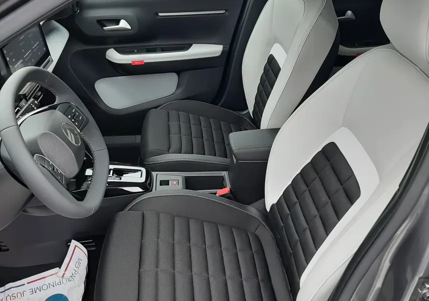 Vue intérieure côté conducteur du Citroën C3 Aircross 2026 gris Mercury, sièges bicolores noir et blanc avec console centrale.