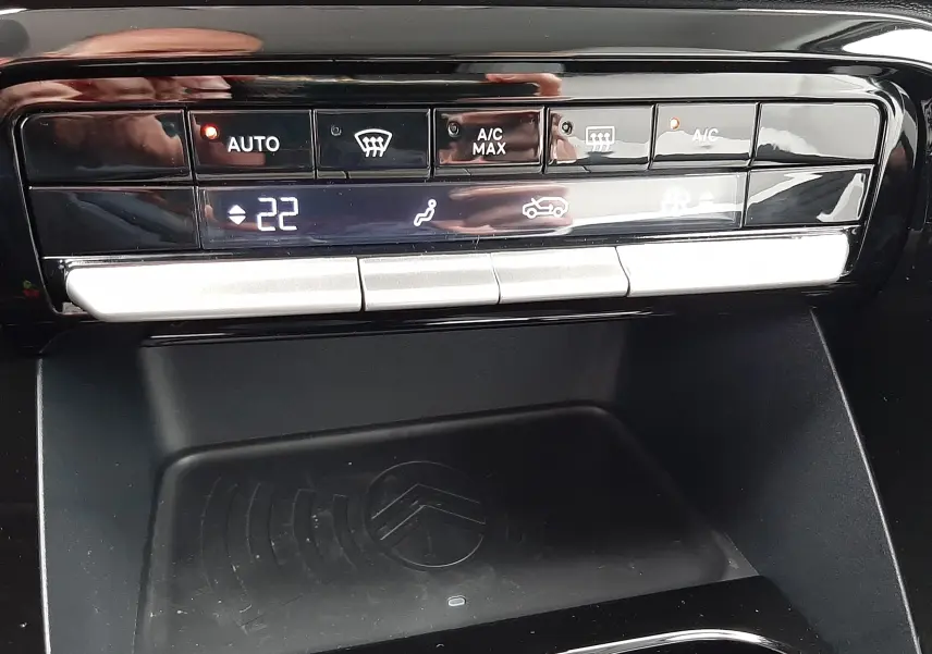 Détail de la console centrale noire du Citroën C3 Aircross 1.2 Hybrid 145 gris Mercury, avec commandes climatisation et zone de recharge.