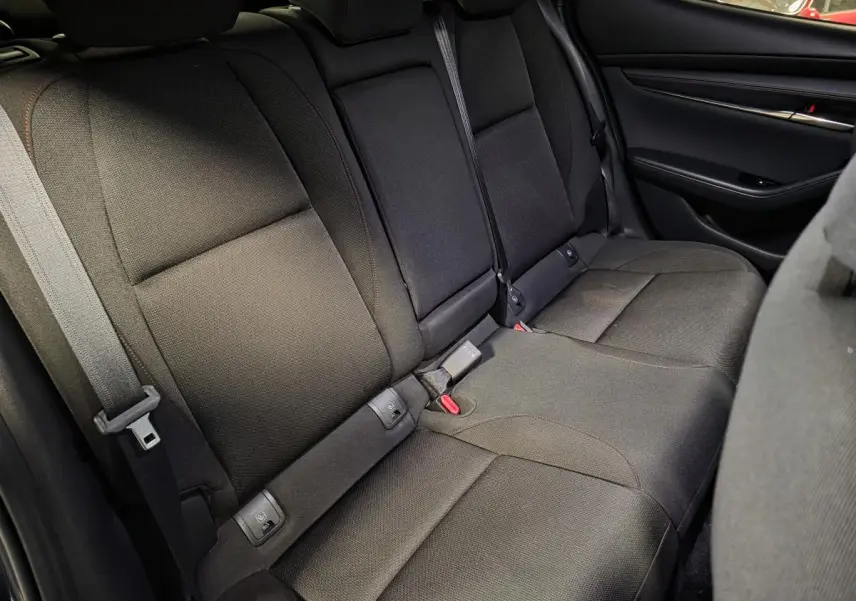 Vue intérieure des sièges arrière en tissu noir avec surpiqûres rouges de la Mazda3 2024, côté droit.