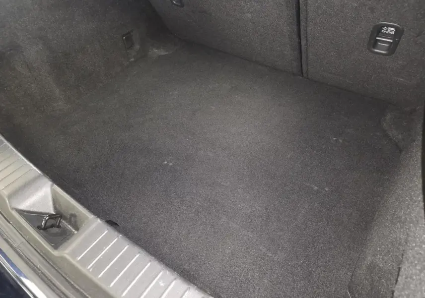 Vue intérieure du coffre spacieux et propre de la Mazda3 2024, revêtement noir uniforme sans objets visibles.