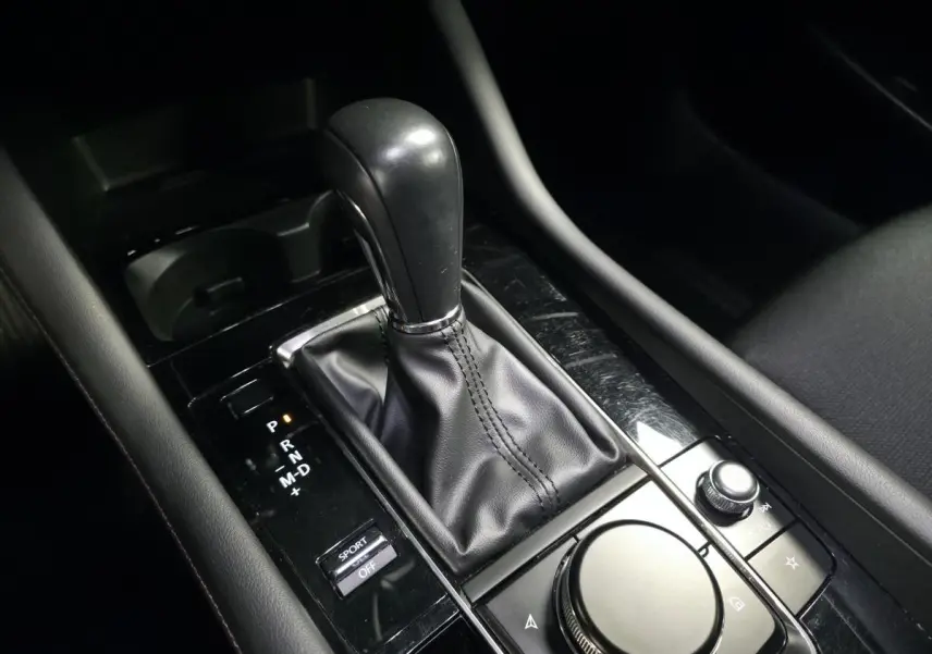 Gros plan sur la console centrale de la Mazda3 2024 bleue, montrant levier de vitesses automatique et commandes multimédia.