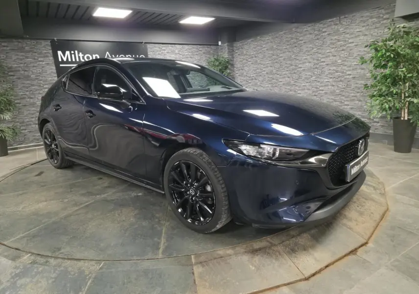 Vue 3/4 avant droite d'une Mazda3 2024 bleu métallisé avec jantes alliage noires et calandre Gloss Black.