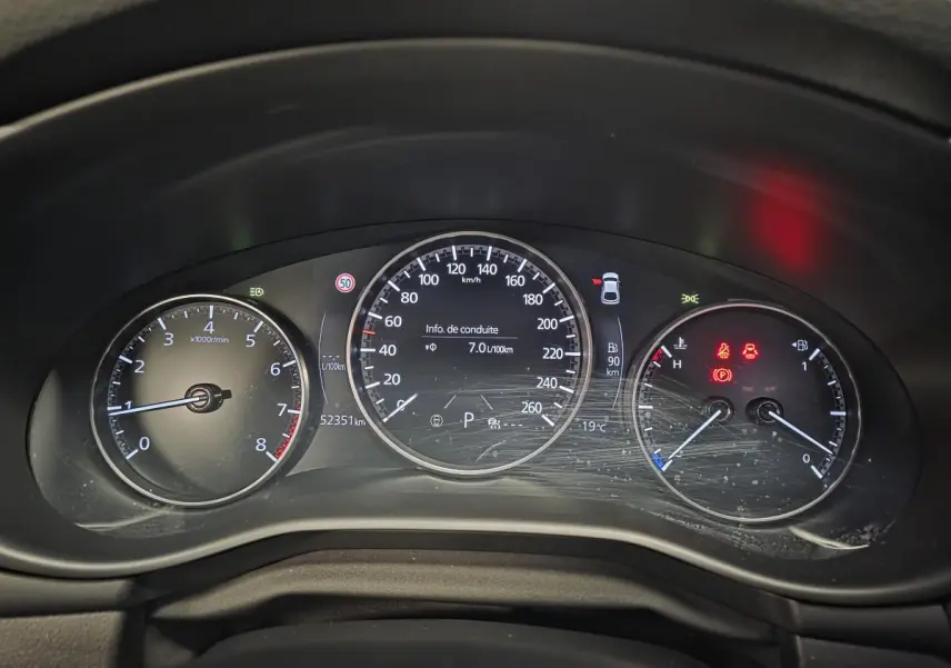 Vue rapprochée du tableau de bord numérique de la Mazda3 2024, affichant compte-tours, vitesse et indicateurs lumineux.
