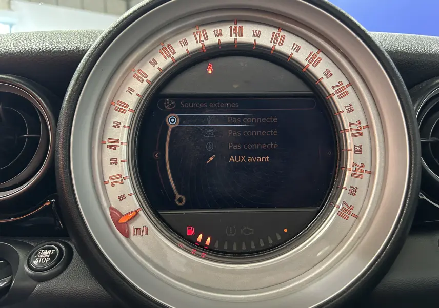 Gros plan sur le compteur central gris de la MINI Cooper Diesel 2011, affichant l'interface multimédia et témoins lumineux.