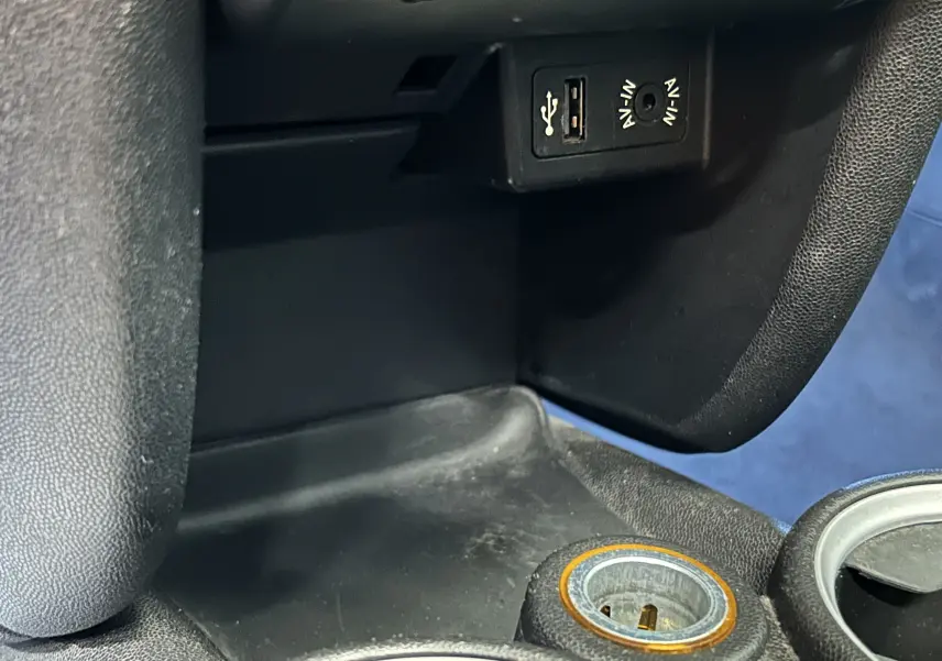 Gros plan sur la console centrale de la MINI Cooper gris, montrant prise USB, entrée audio et allume-cigare.