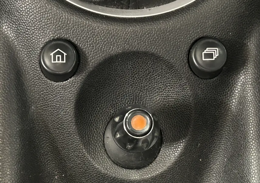 Gros plan sur les boutons de commande du tableau de bord noir d’une MINI Cooper gris 2011, avec icônes maison et fenêtres superposées.