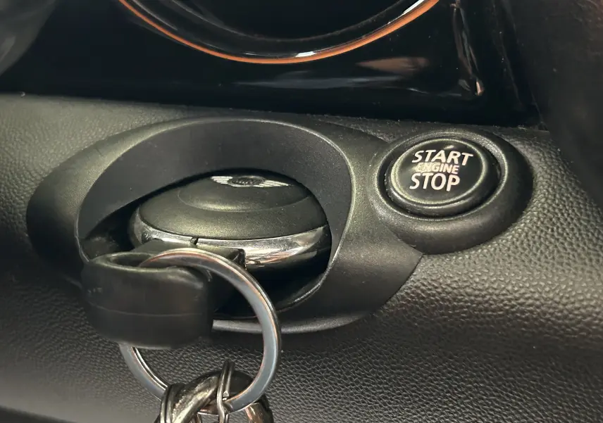 Gros plan intérieur sur la clé MINI insérée près du bouton Start Engine Stop sur tableau de bord noir.