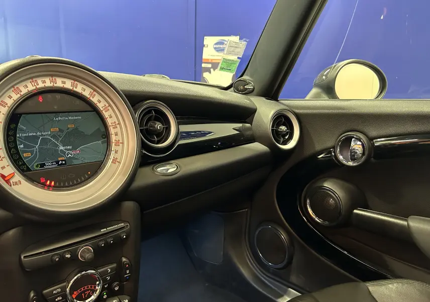 Vue intérieure côté passager de la MINI Cooper gris, avec tableau de bord et écran GPS circulaire au centre.