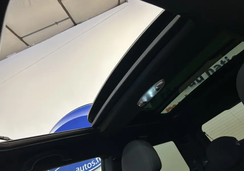 Vue intérieure du toit ouvrant panoramique de la MINI Cooper gris, avec sièges avant visibles en partie.
